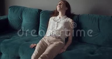 年轻疲惫的女人坐在沙发上头痛。